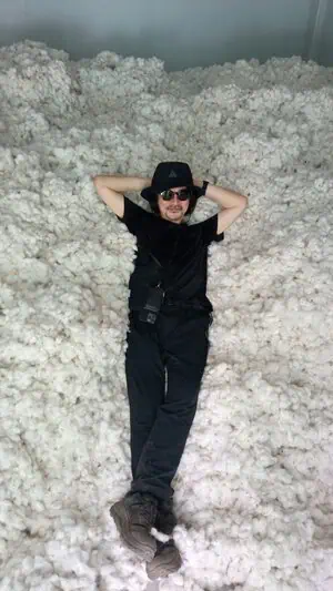 Man in black clothing and sunglasses relaxing on a large pile of organic pima cotton.