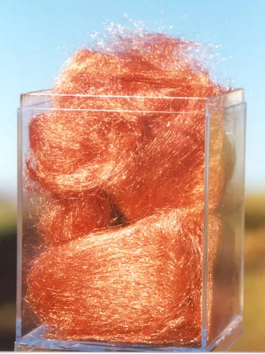 Shiny copper-colored Angelina fiber stored in a transparent display box under sunlight.